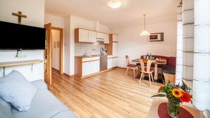 A modern apartment with a kitchen, dining area, and living room. - Apartment "Langeshof - Löwenzahn" with Mountain View, Garden & Wi-Fi (Kuens bei Meran, Südtirol - Italien)
