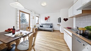 A modern kitchen with a dining area, wooden flooring, and a sofa. - Apartment "Langeshof - Löwenzahn" with Mountain View, Garden & Wi-Fi (Kuens bei Meran, Südtirol - Italien)