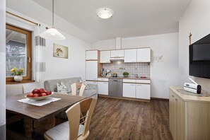 Une cuisine moderne avec des meubles blancs, une table à manger en bois et un lave-vaisselle encastré.
