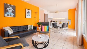 A modern living room with a black sofa, a round coffee table, and a dining area with a white table and chairs. - Vacation Apartment “La Vega de Lanzarote 4” with Sea View, Pool & Wi-Fi (Tías)