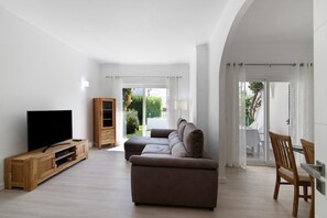 A living room with a sofa, TV stand, and a dining area with chairs.