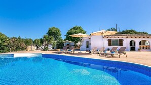A swimming pool with lounge chairs and umbrellas, a white building with arches, and trees in the background. - Finca Llonguet with Mountain View, Pool & Wi-Fi (Capdepera)
