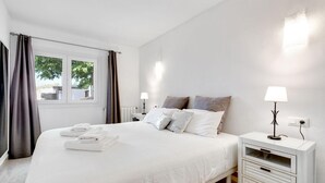 A hotel room with a bed, two bedside tables, a window with curtains, and a view of the outside. - Finca Llonguet with Mountain View, Pool & Wi-Fi (Capdepera)