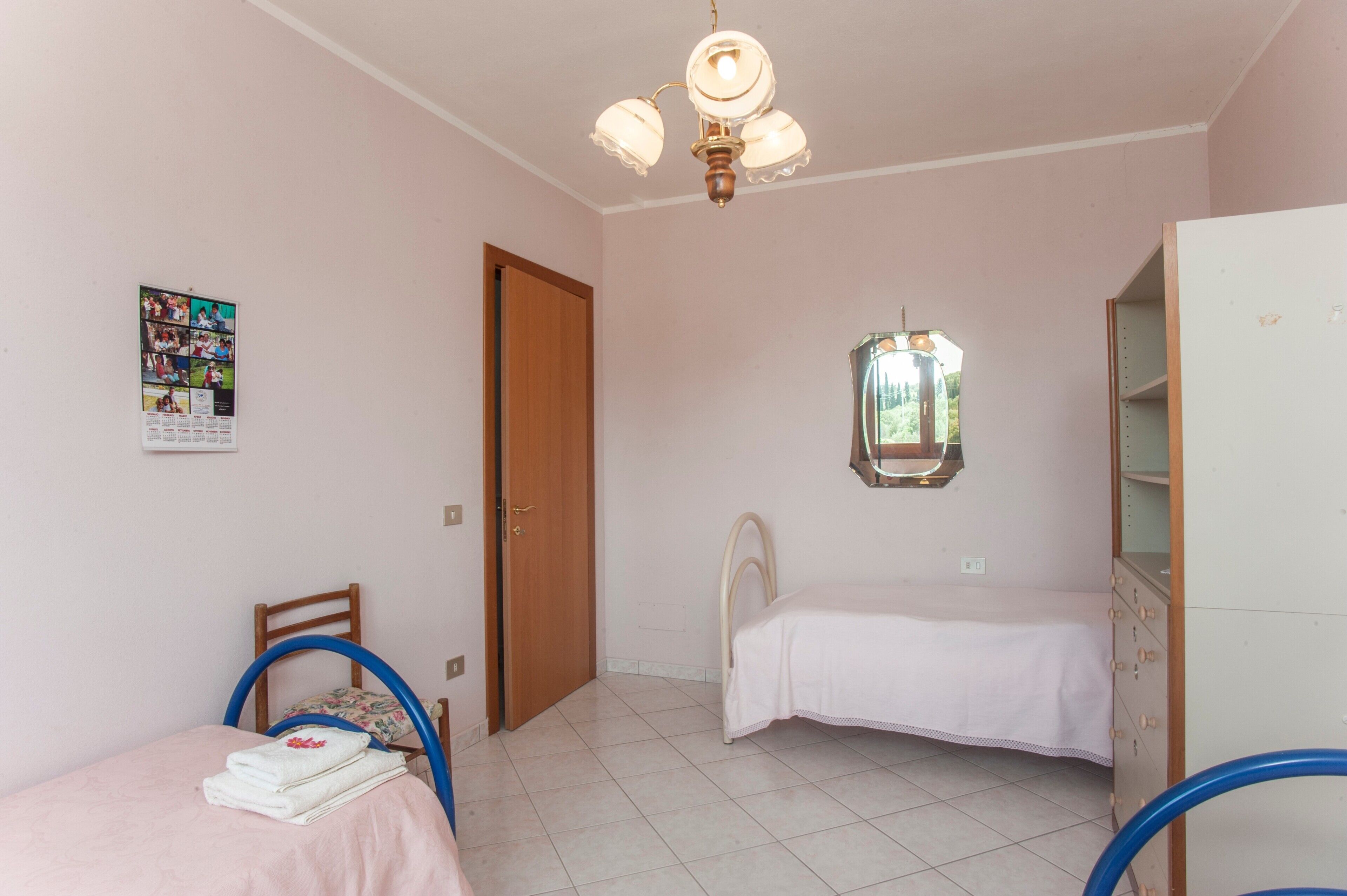 Ein Schlafzimmer mit Bett, Stuhl, Kommode, Deckenventilator und Fenster.