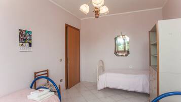 Ein Schlafzimmer mit Bett, Stuhl, Kommode, Deckenventilator und Fenster.