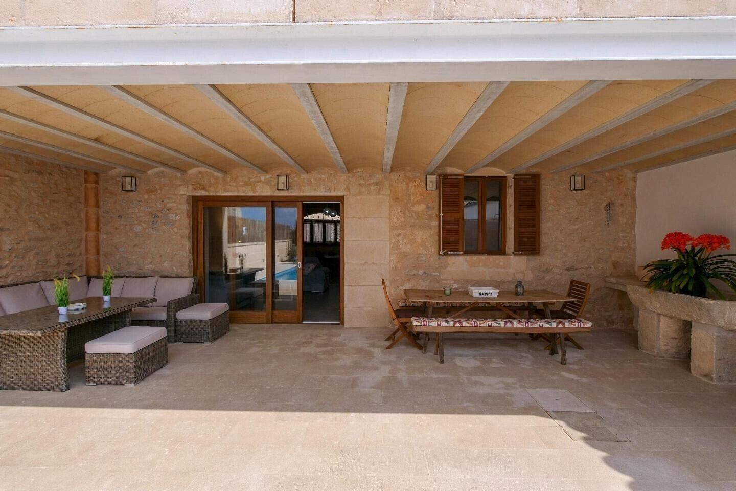 Un patio al aire libre con una mesa, sillas, una puerta corrediza de vidrio y un muro de piedra.