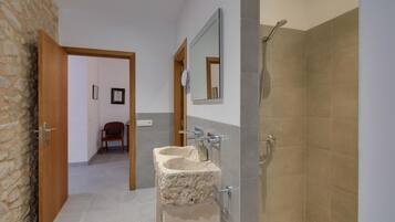 Un baño con un lavabo de piedra, ducha y espejo.