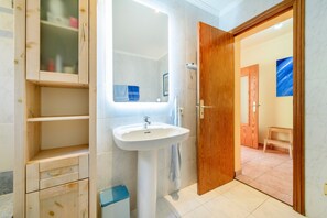 A bathroom with a wooden cabinet, a white sink, and a mirror. -  Vacation Home Casa Folara with Sea View, Pool, Wi-Fi, Terrace & Garden (Cala Llombards)