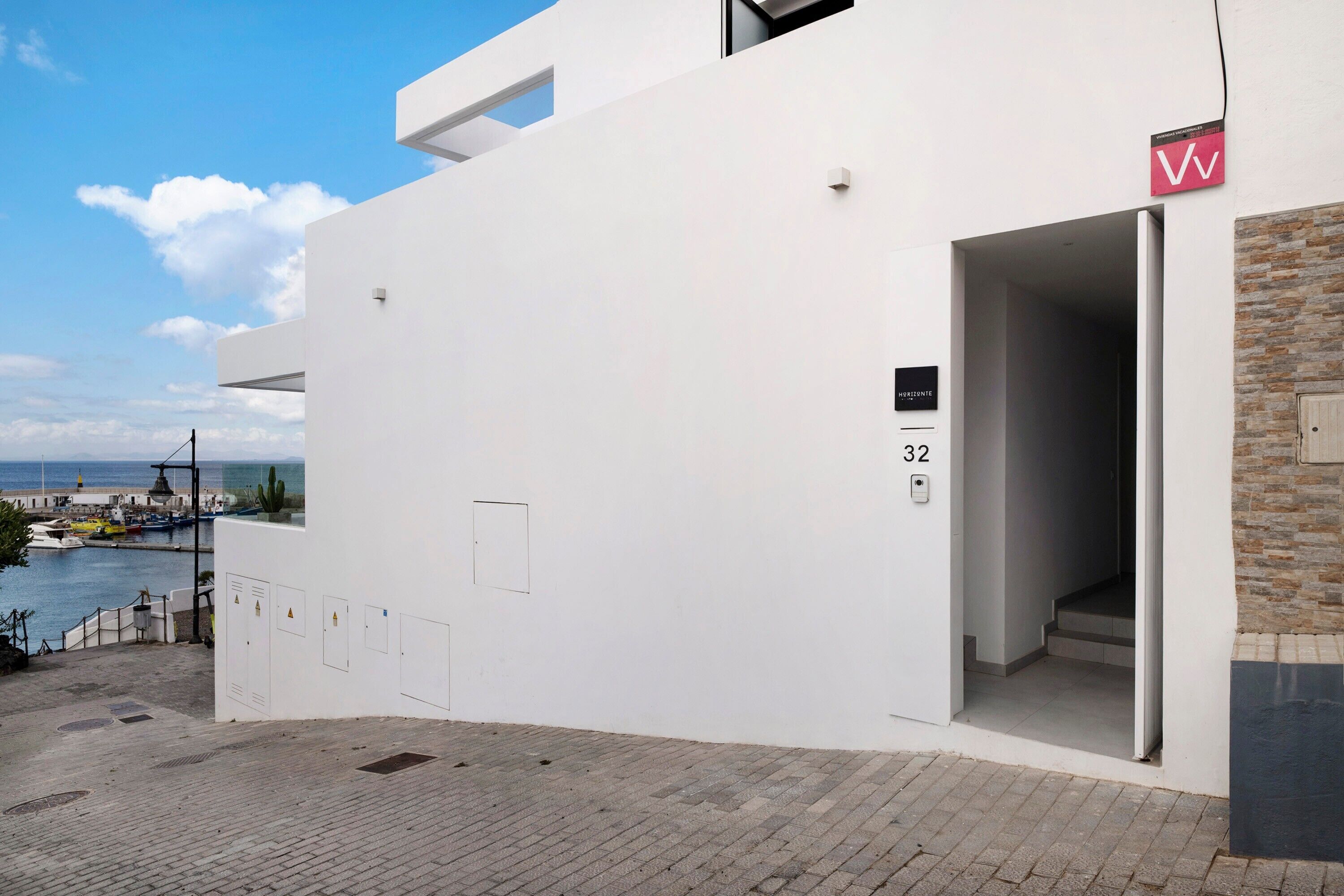 Um edifício moderno com fachada branca, entrada visível e placa com o número 32.
