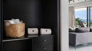 Een moderne kamer met een donkere garderobe, een rieten mand en twee handdoeken op een plank.