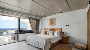 Een moderne slaapkamer met een groot bed, uitzicht op zee en een balkon.