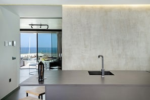 A modern kitchen with a large window, a view of the sea, and a minimalist design.