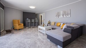 A modern living room with a sofa, armchair, coffee table, and a decorative wall piece.