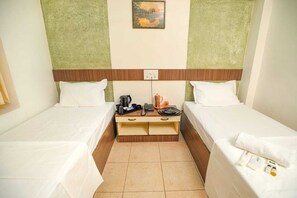 A hotel room with two single beds, a wooden nightstand with a kettle, a phone, and a cup. - Hotel Sapthagiri Nest (Coimbatore)