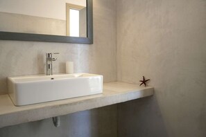 Ein Badezimmer mit einem weißen Waschbecken, einem Spiegel und einer Meerstern-Dekoration.