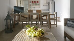 Een eetgedeelte met een tafel gedekt voor twee personen, een televisie en een keuken op de achtergrond.