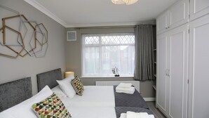 A hotel room with a large bed, a window with curtains, a radiator, and a wardrobe.