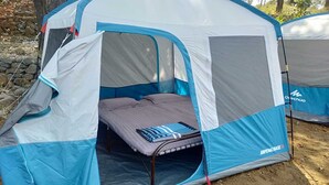Ein Zelt mit einem Bett im Inneren, in blau-weißem Farbschema, mit dem Schriftzug 'Oechua' an der Seite.