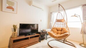 A modern living room with a TV on a wooden cabinet, a hanging chair, and a large window with curtains. - Purple (Sapporo)