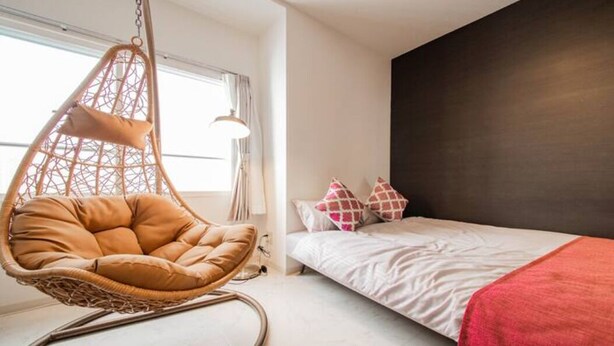 A bedroom with a hanging chair, a bed with pillows, and a window with curtains. - Purple (Sapporo)