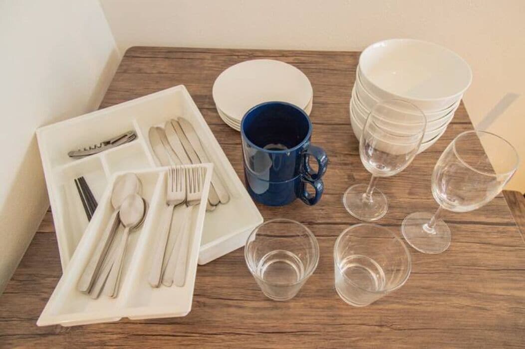 A dining setup with a white plate set, a blue mug, and stacked white plates on a wooden table.