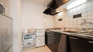 A modern kitchen with white and black tiles, stainless steel appliances, and a visible oven and dishwasher. - Purple (Sapporo)