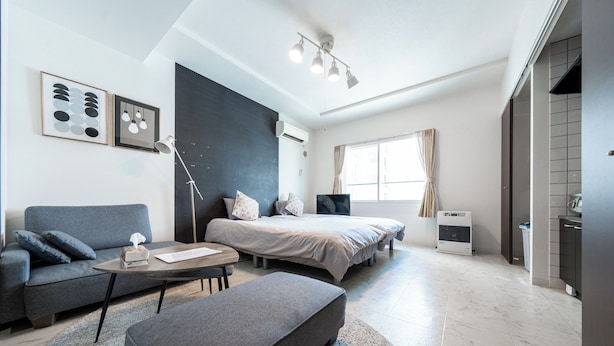 A modern, well-lit bedroom with a bed, bedside table, and a large window. - Yellow (Sapporo)
