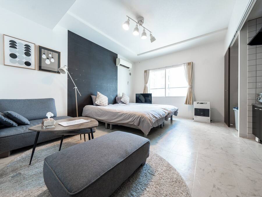 Un dormitorio moderno y bien iluminado con cama, mesita de noche y un gran ventanal.