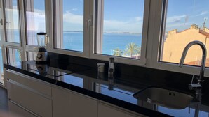 Eine Küche mit einem großen Fenster mit Meerblick, einem Mixer, einem Wasserkocher und einer Spüle.