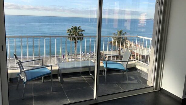 Ein Balkon mit Meerblick, zwei Stühle und ein kleiner Tisch.