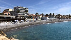 Ein Hotel direkt am Strand mit mehreren Etagen, einem Sandstrand und klarem, blauem Wasser.