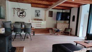 Una sala de estar con chimenea, dos sillones, un sofá y un televisor.