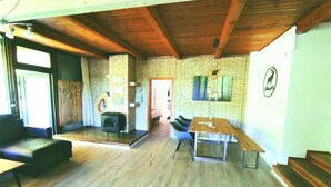 Una habitación amplia con techo de madera, pared de ladrillo y un ventanal grande.