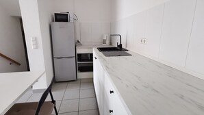 A modern kitchen with white cabinetry, a built-in microwave, a coffee maker, and a black faucet. - Apartment Close to Lake Ferienwohnung Seenah (Sipplingen)