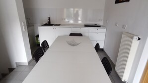 A modern kitchen with white cabinets, a dining table, and chairs. - Apartment Close to Lake Ferienwohnung Seenah (Sipplingen)
