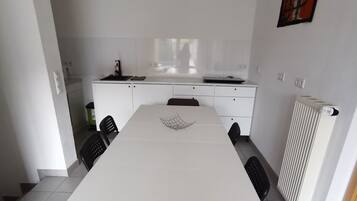A modern kitchen with white cabinets, a dining table, and chairs.