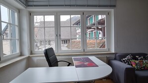 A room with a large window, a table, a chair, and a sofa. - Apartment Close to Lake Ferienwohnung Seenah (Sipplingen)