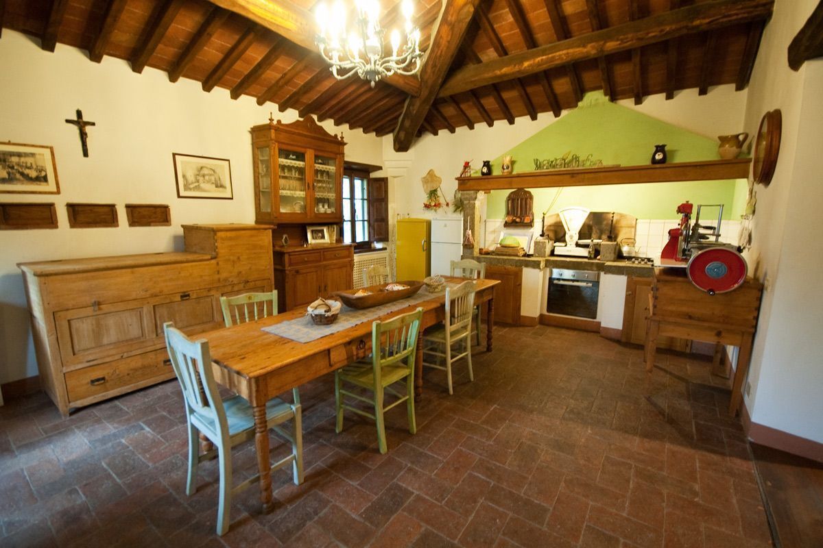 Un comedor rústico con una mesa y sillas de madera, un aparador de madera y una cruz en la pared.