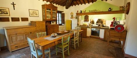 Un comedor rústico con una mesa y sillas de madera, un aparador de madera y una cruz en la pared.