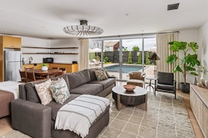 A modern living room with a sofa, coffee table, and a dining area with chairs.