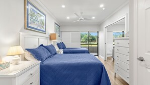 Un dormitorio con dos camas, una mesita de noche, un aparador y un ventilador de techo.