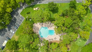 Vista aérea de una propiedad con piscina rodeada de árboles, aparcamiento y campo de golf.