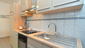 Una cocina moderna con un lavamanos de acero inoxidable, horno empotrado y campana extractora.