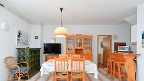 A dining area with a wooden table and chairs, a television, a cabinet, and a microwave.