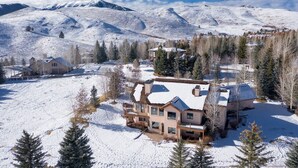 Paesaggio montano innevato con una grande casa circondata da alberi.