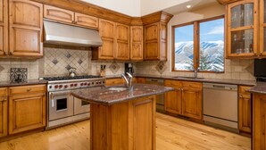 Una cucina con mobili in legno, un piano di lavoro in granito, un fornello e una lavastoviglie.