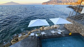 A pool area with white umbrellas, lounge chairs, and a view of the sea. - Beachfront Villa Sorrento & private sea access (Sorrento)