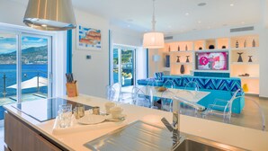 A modern kitchen with a large island, clear chairs, and a view of the sea. - Beachfront Villa Sorrento & private sea access (Sorrento)