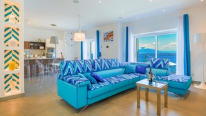 A modern living room with a large sofa, a dining area, and a view of the sea. - Beachfront Villa Sorrento & private sea access (Sorrento)