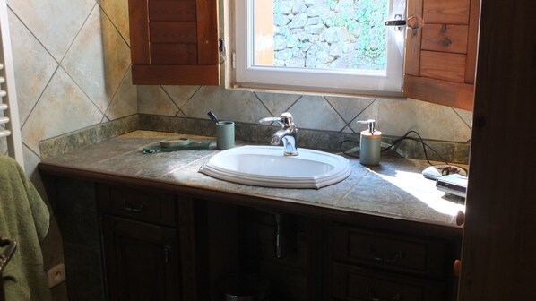 A bathroom with a white sink, a window, and a stone wall. - Maison Avec Grand Terrain (Chassiers)
